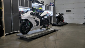 Suzuki GSX-R blanche sur un élévateur de maintenance.