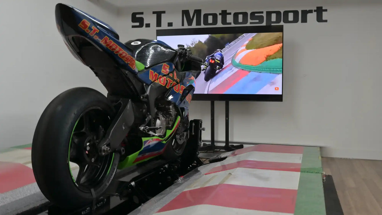 Moto de course montée sur une plateforme de simulateur avec des graphismes colorés.