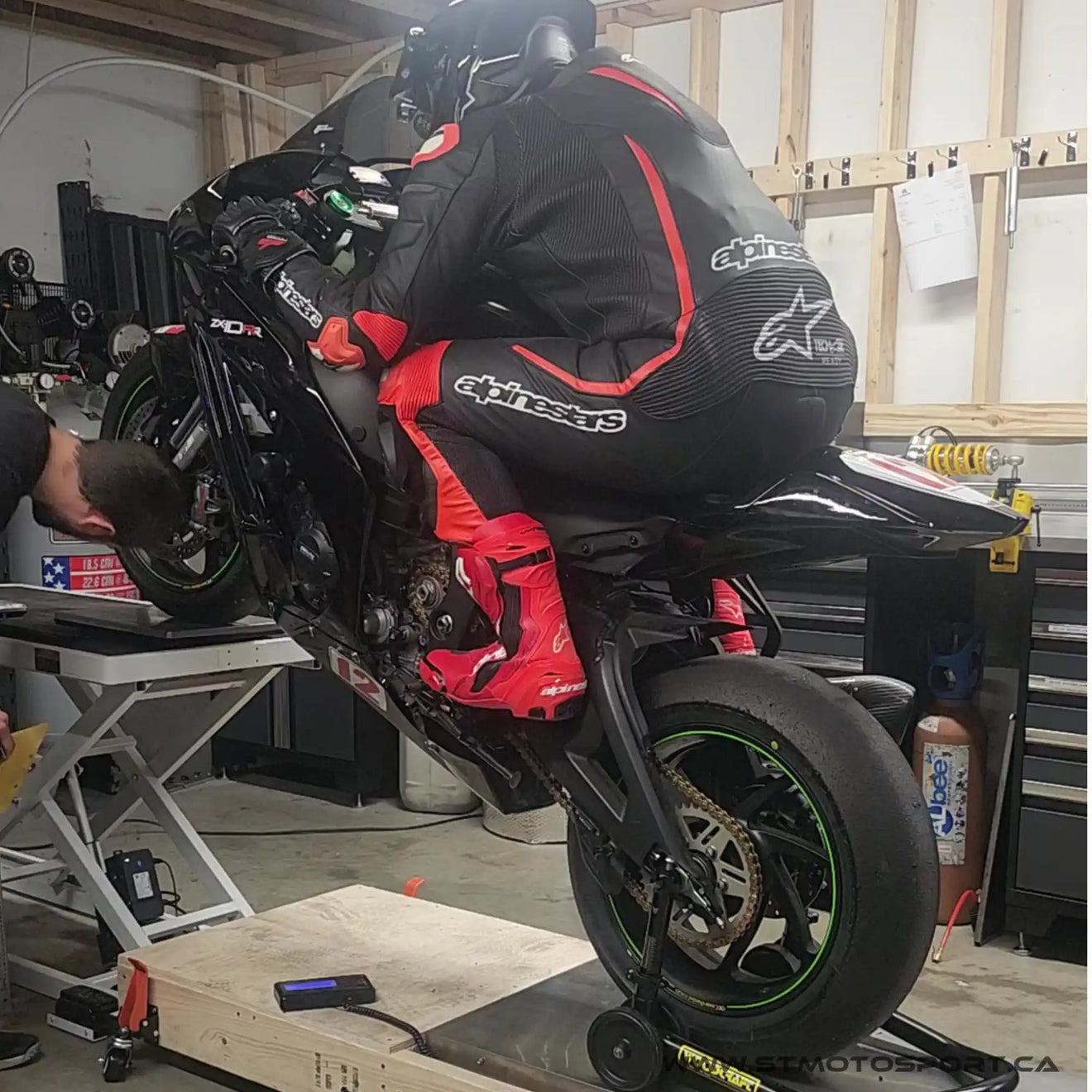 Moto noire et rouge sur un élévateur de maintenance réalisant un wheeling.