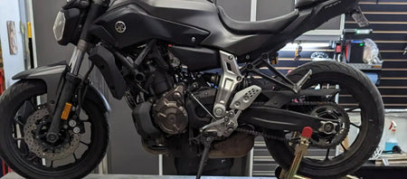 Moto Yamaha MT-07 noire avec des composants mécaniques exposés et un design sportif.